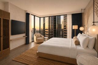 A modern hotel room features a king-sized bed, cozy seating, large windows with city views, and warm neutral tones, creating a relaxing atmosphere.
