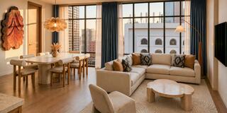 A modern, stylish living space with large windows, natural light, minimalist furniture, and warm tones, creating a cozy atmosphere.