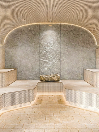 A serene spa setting featuring textured stone walls, elegant lighting, and minimalist design elements, creating a tranquil atmosphere.