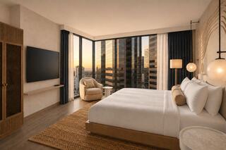 A modern bedroom features a plush bed, cozy seating, and large windows showcasing a city skyline at sunset. Elegance meets comfort.