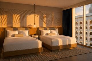 A stylish hotel room features two queen beds, soft lighting, and modern decor, creating a warm and inviting atmosphere.