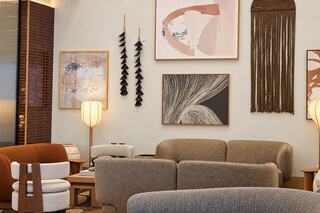 A cozy, modern lounge features earthy tones, stylish seating, and various artworks, creating a welcoming atmosphere perfect for relaxation.