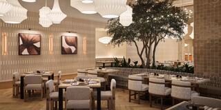 An elegant dining area features chic wooden tables, soft lighting, art on the walls, and a central tree adding a touch of nature.