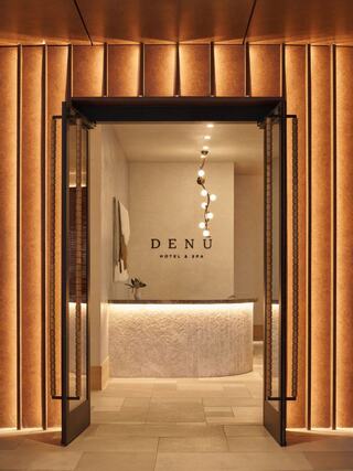 A stylish hotel and spa entrance with warm lighting, elegant decor, and a minimalist reception area, inviting guests into a serene atmosphere.