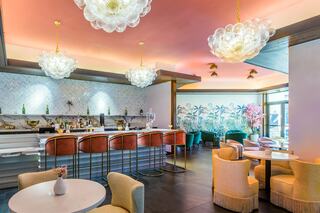 A stylish bar area features elegant seating, artistic decor, and unique lighting, creating a vibrant yet relaxed atmosphere.
