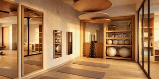A serene fitness or yoga studio featuring wooden accents, large mirrors, exercise equipment, and natural light filtering in.