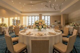 A beautifully arranged banquet hall featuring elegant tables set for a formal event, adorned with floral centerpieces and soft lighting.