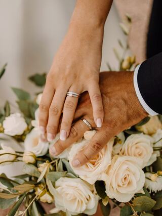 A woman smiles elegantly in a flowing wedding dress, illuminated by warm sunlight against a rustic backdrop.