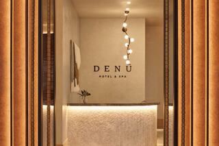 A sleek hotel reception area features soft lighting, a modern desk, with the "DENÜ Hotel & Spa" sign prominently displayed.