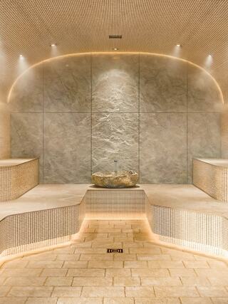 A serene, modern spa interior featuring gentle curves, warm lighting, and minimalist design with stone accents and built-in seating.