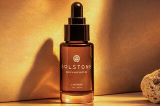 A bottle of lavender body and massage oil, elegantly lit against a warm background, exuding a calming and luxurious essence.