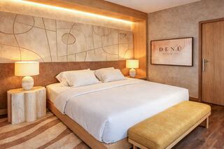 A modern hotel room featuring a king-sized bed, stylish decor, warm lighting, and contemporary furniture, creating a cozy atmosphere.