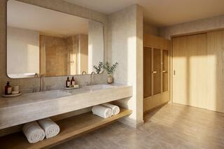 A modern bathroom features a double sink vanity, wooden accents, neatly rolled towels, and a warm, inviting atmosphere.