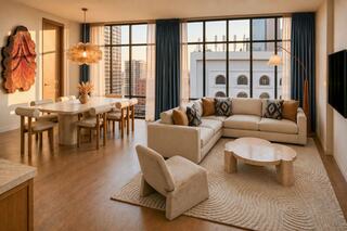 Stylish living space featuring a modern sectional sofa, a light wooden dining table, warm decor, large windows, and city views.