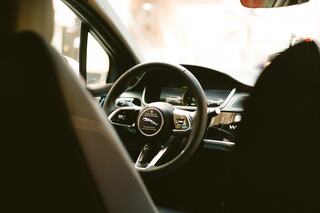 A sleek car interior showcases a modern steering wheel and dashboard, hinting at advanced technology and stylish design.