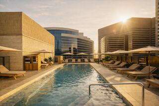 A serene rooftop pool with sun loungers, surrounded by modern buildings, illuminated by a warm sunset glow.