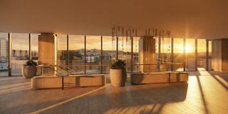 A spacious, modern interior features large windows displaying a sunset, complemented by elegant planters and minimalist furnishings.