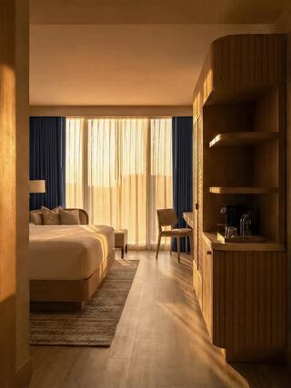 A stylish bedroom features warm lighting, soft curtains, and modern furnishings, creating a cozy and inviting atmosphere.